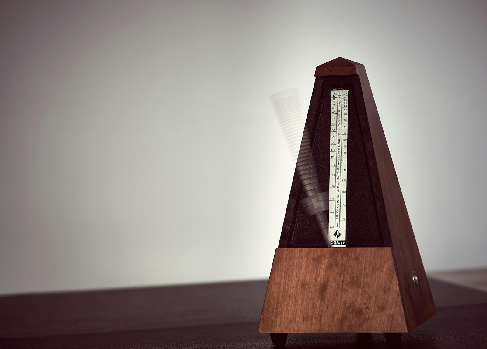 Close-up of a moving wooden metronome, signalling the cadence behind repeatable revenue